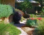 Colorful plants and a fountain along a walkway add interest and dimension Front yard with fountain closeup